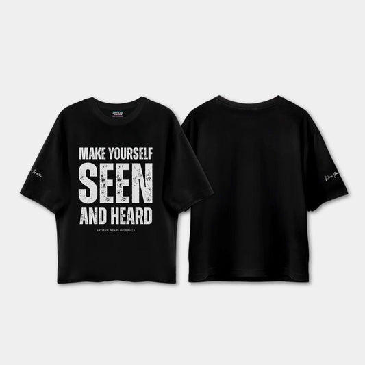 Black t-shirt with text 'MAKE YOURSELF SEEN AND HEARD' on a light gray background
